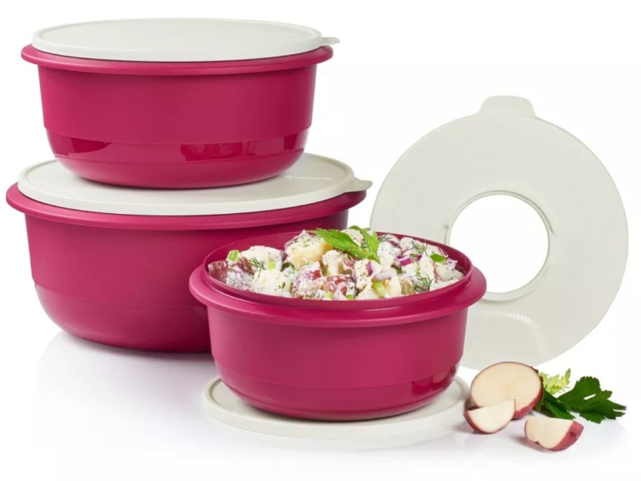 set of 4 pink Tupperware mixing bowls with white lids that have a removable center for using with a mixer, one bowl is open with food in it