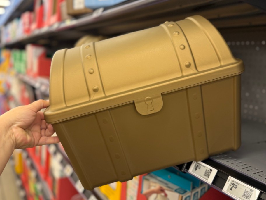 hand holding a gold plastic rewards chest near a store shelf