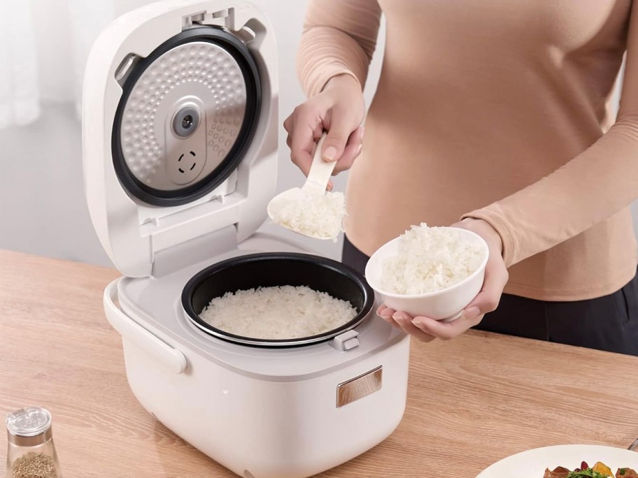 woman scooping white rice out of rice cooker