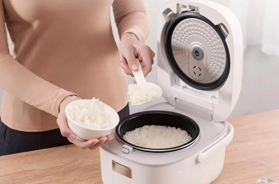 person scooping rice from rice cooker