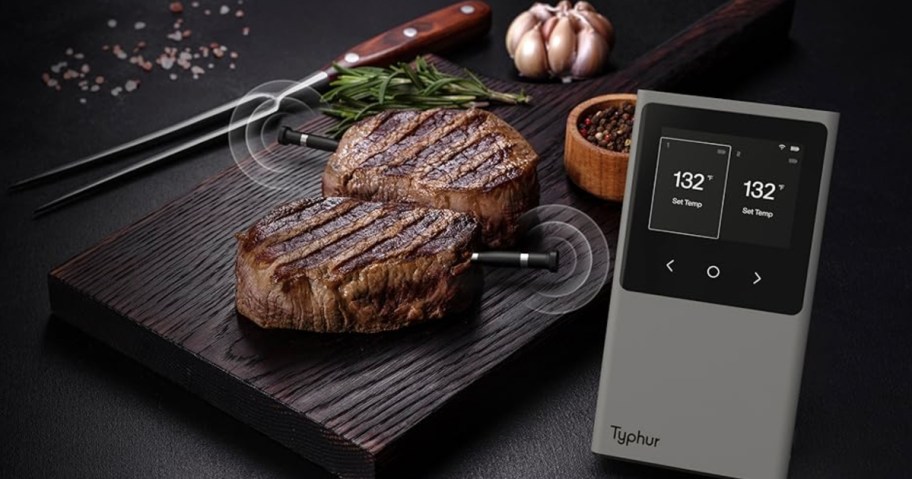 steaks on cutting board with meat thermometer in them and base on table
