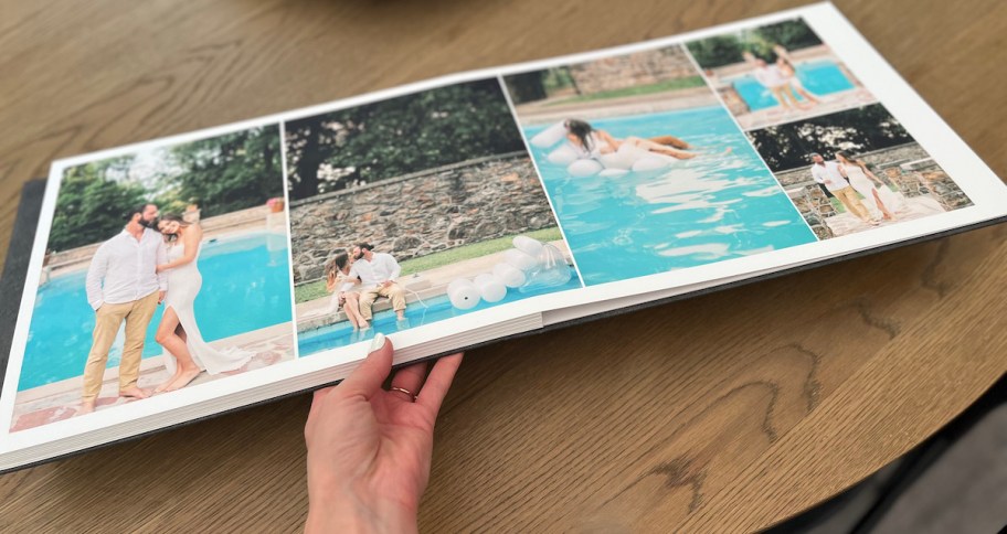 hand holding a photo album on wood table