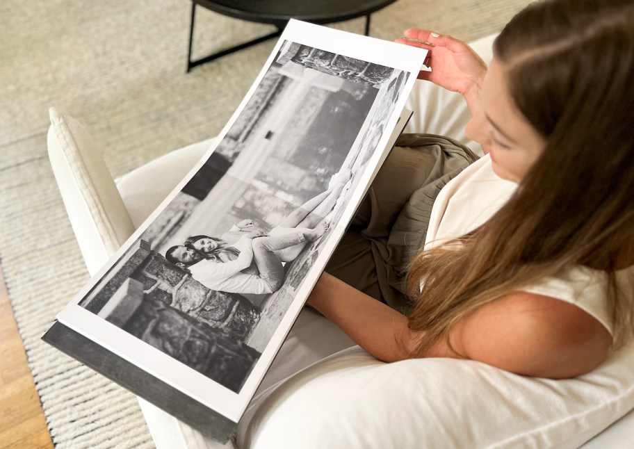 woman sitting on couch flipping through lay flat photo album 