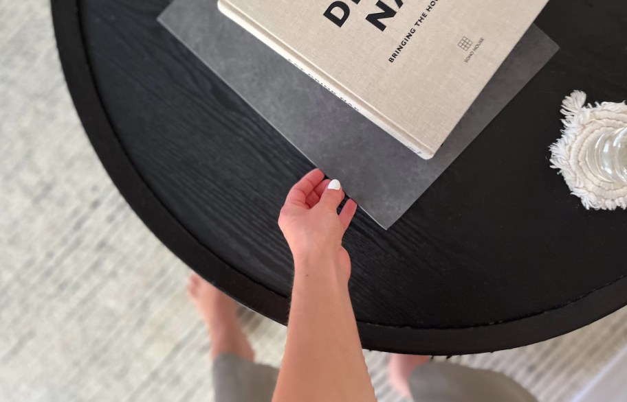 hand holding edge of black walgreens photo book on black wood coffee table