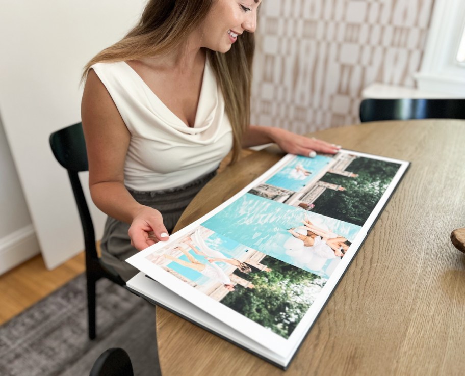 woman sitting at wood table flipping through photo album book