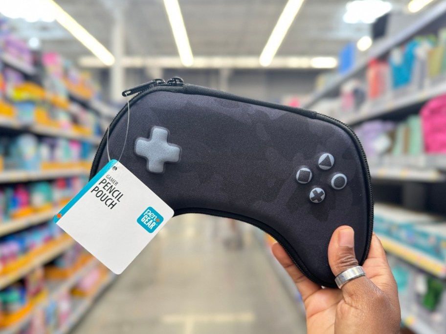 hand holding a video game controller shaped pencil case in a store aisle