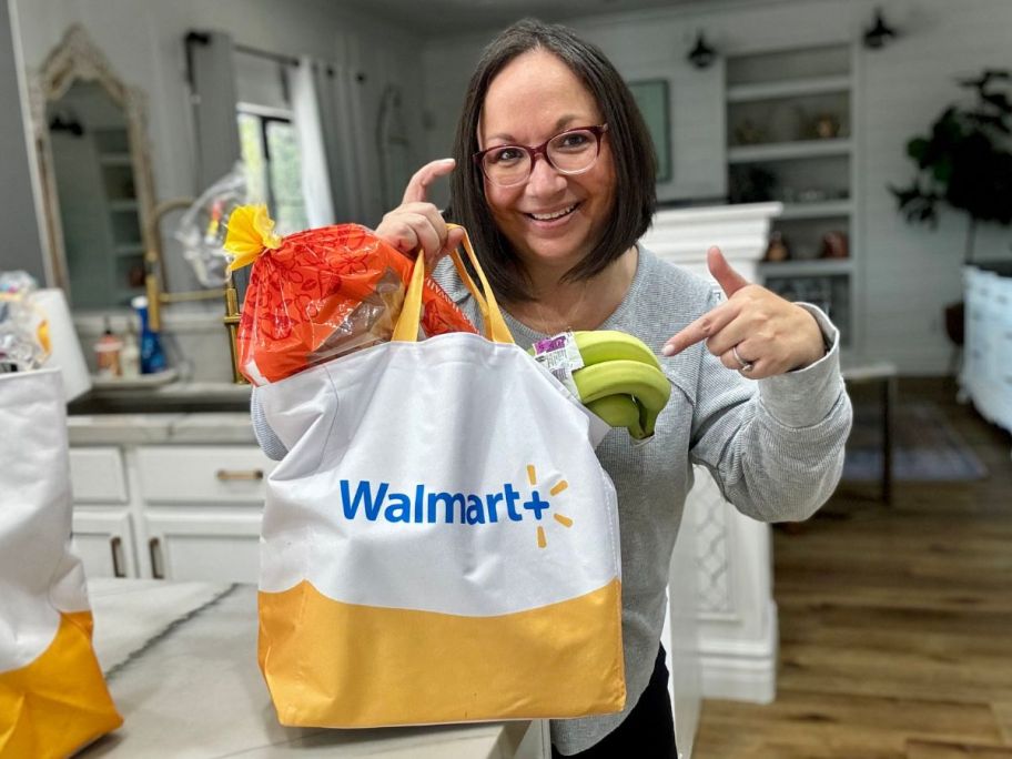 woman in kitchen with a Walmart+ bag filled with groceries