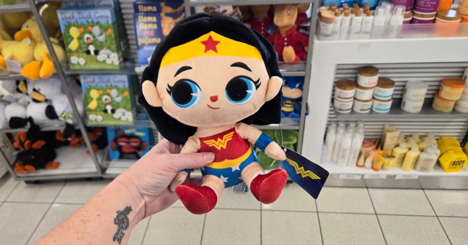 hand holding a kohls cares plush wonder woman in a store aisle