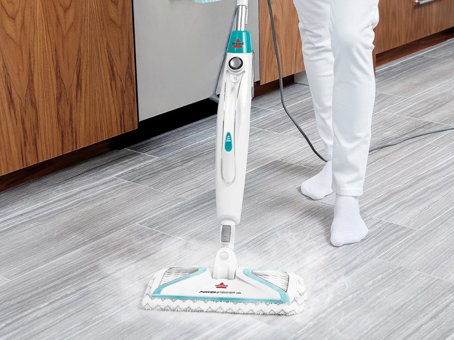 person mopping a laminate wood floor with a Bissell steam mop