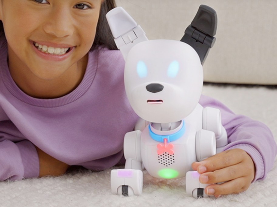 little girl playing with a white robot dog that lights up