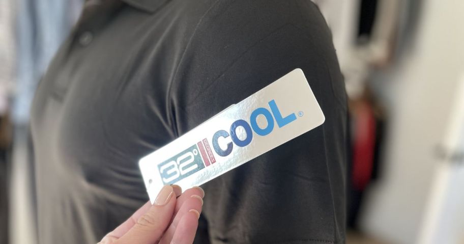 Hand holding a 32 Degrees Cool tag on a polo shirt for men