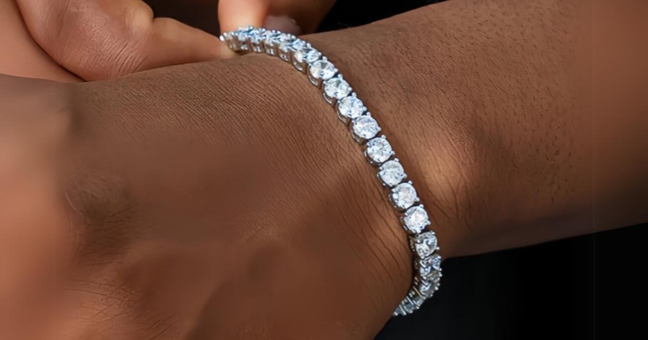 person's hand wearing a diamond tennis bracelet