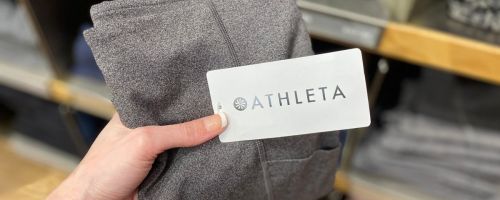 Hand holding up a pair of brand new Athleta Leggings with the tag on them