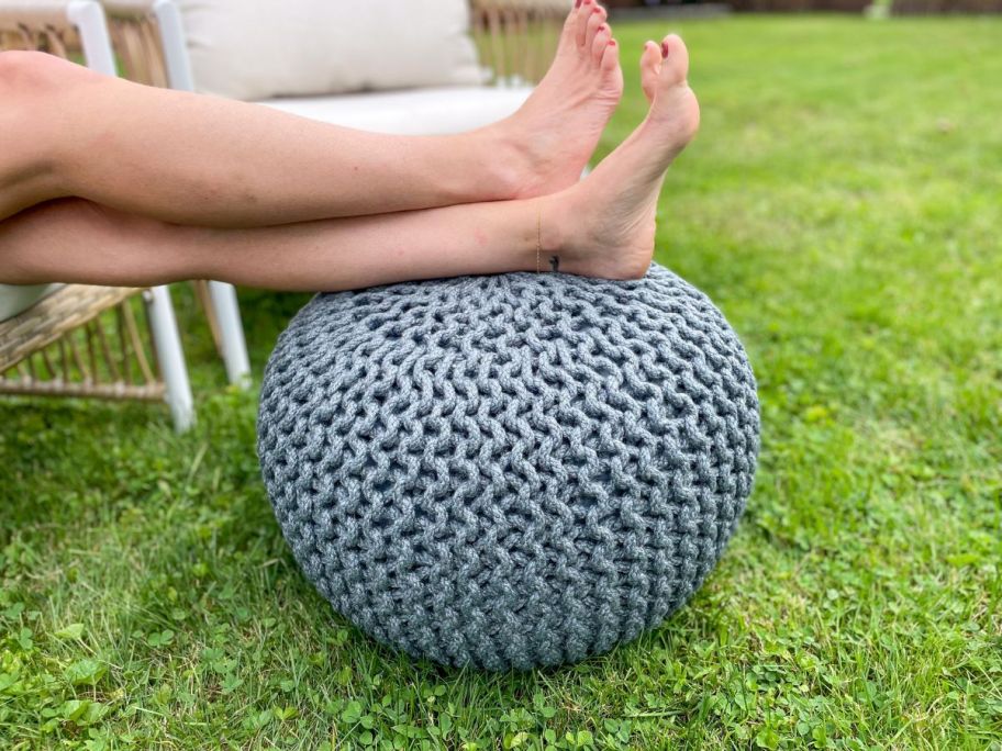 A woman resting her feet upon a Barbara King Textured Woven Pouf Ottoman