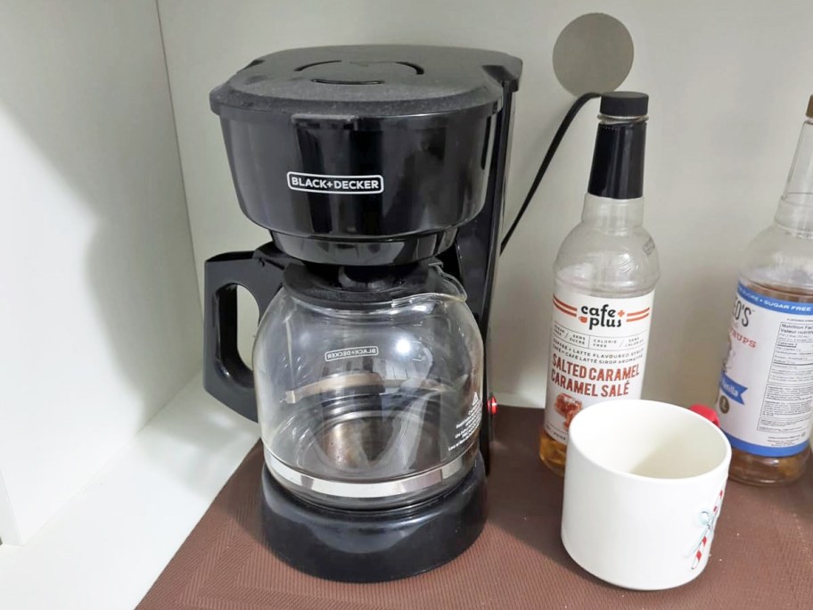 Black+Decker 12-Cup Coffee Maker on counter near mug and syrup