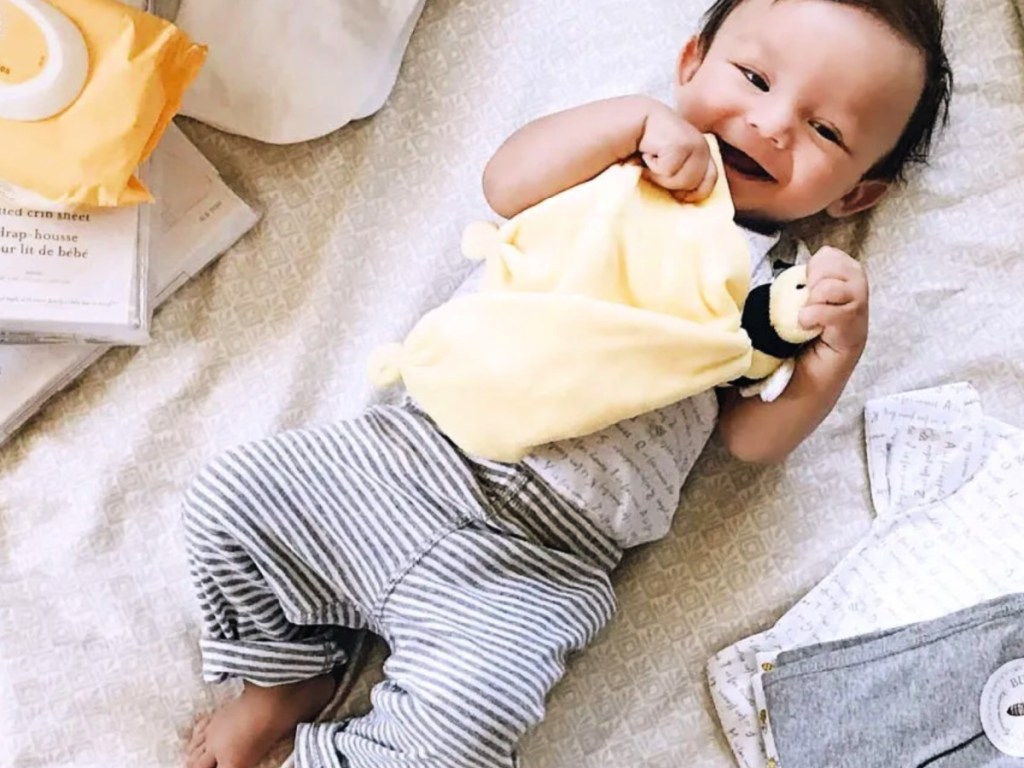 baby on bed chewing on Burts Bees Lovey