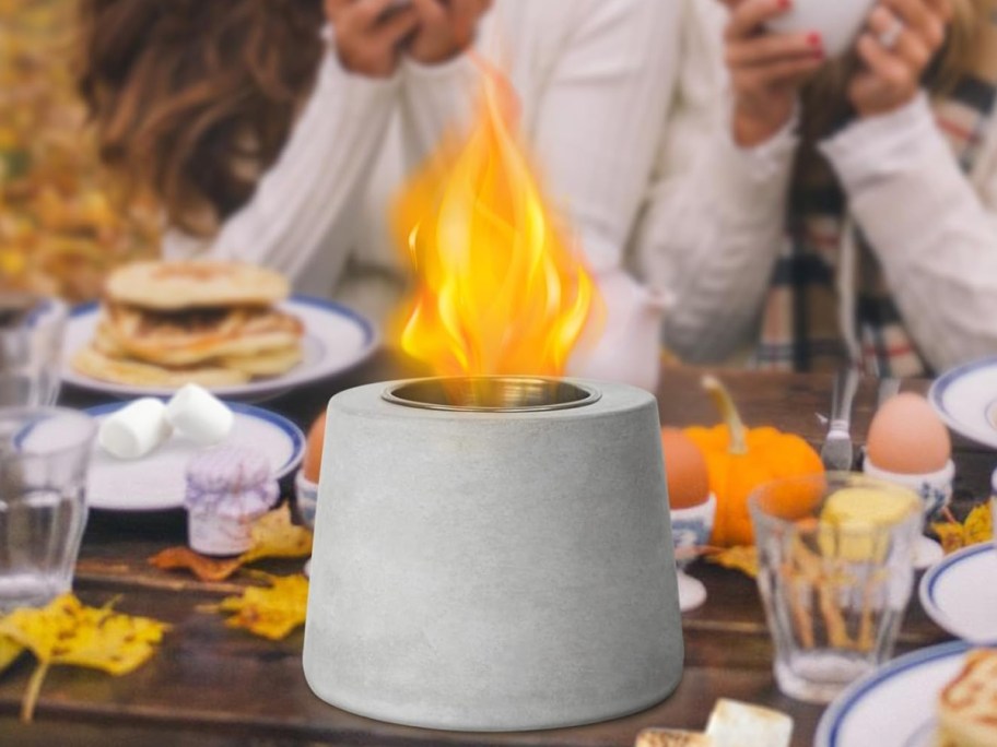 Concrete Small Table Top Firepit on a table displayed with people behind it