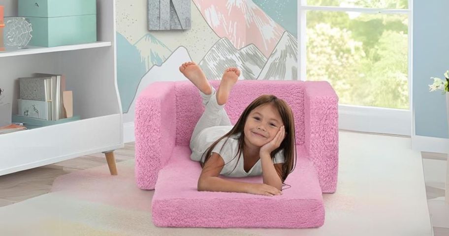 girl laying on Delta Children Cozee Sherpa 2-in-1 Flip Chair