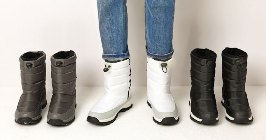 person wearing white snow boots with matching grey and black pairs on either side of them