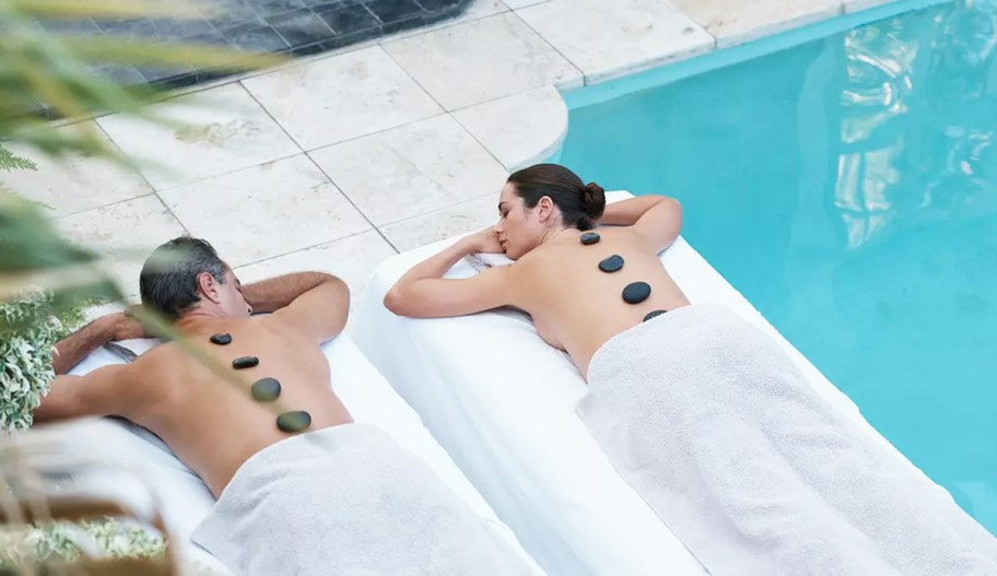 couple getting hot stone massage by pool