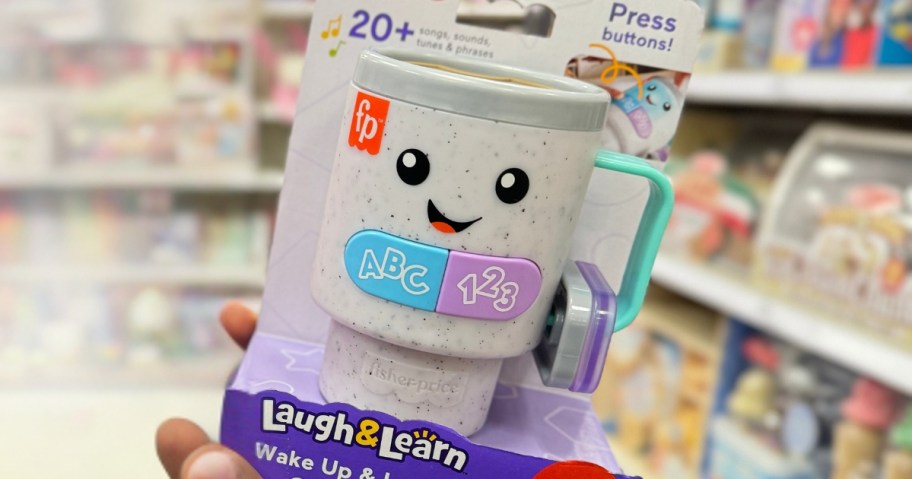 hand holding a Fisher-Price Laugh & Learn Wake Up & Learn Coffee Mug in a store aisle