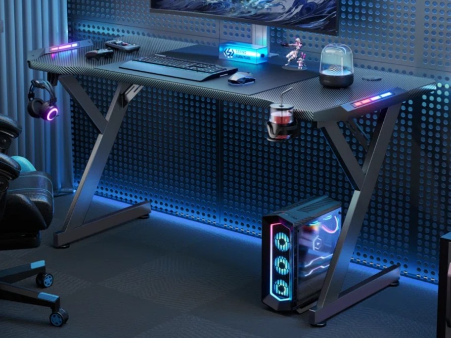 a black steel gaming desk with a monitor, keyboard, and mouse on top, it has colorful LED lights around it