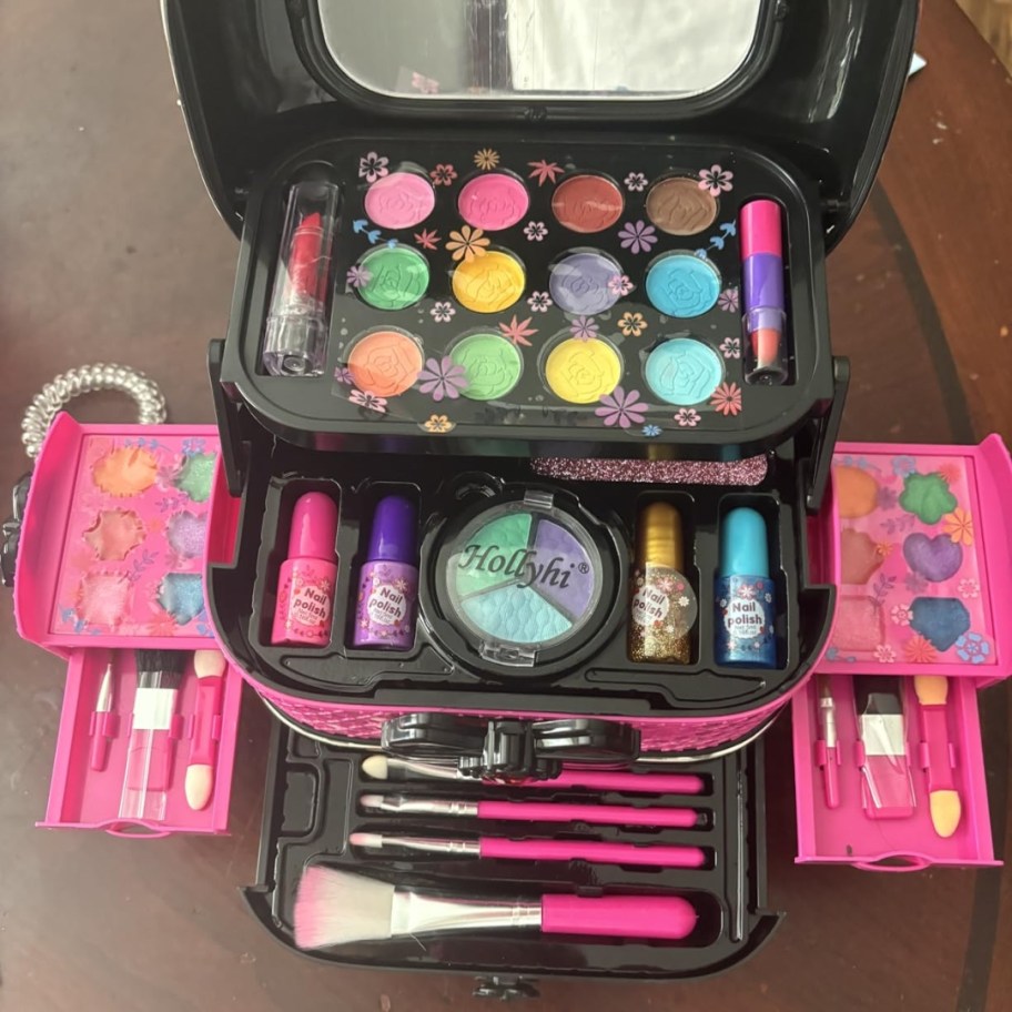 a hot pink and black kid's makeup case kit with compartments open showing all the makeup