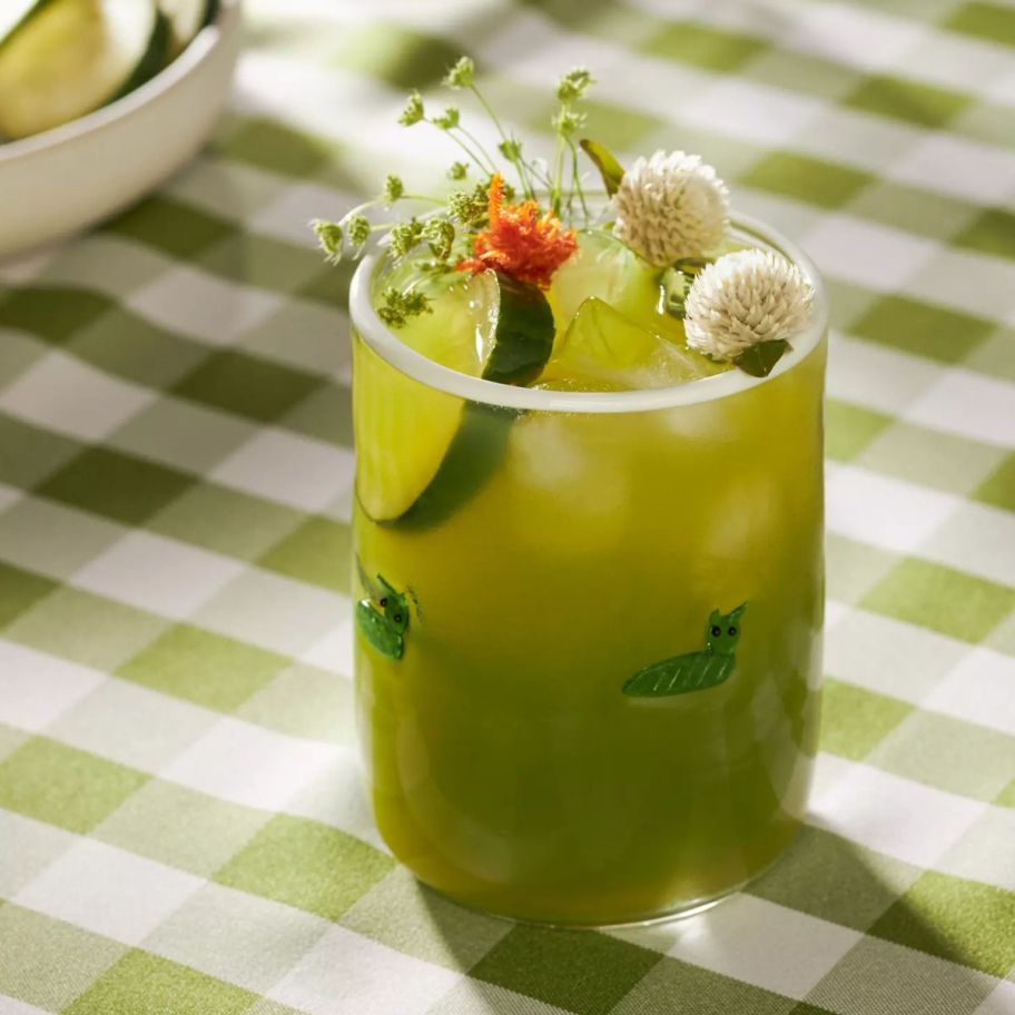 a handmade juice glass with a caterpillar motif with a garnished green drink 