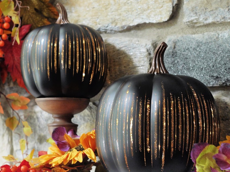 two black Illuminated Starry Night Pumpkins surrounded by fall decor