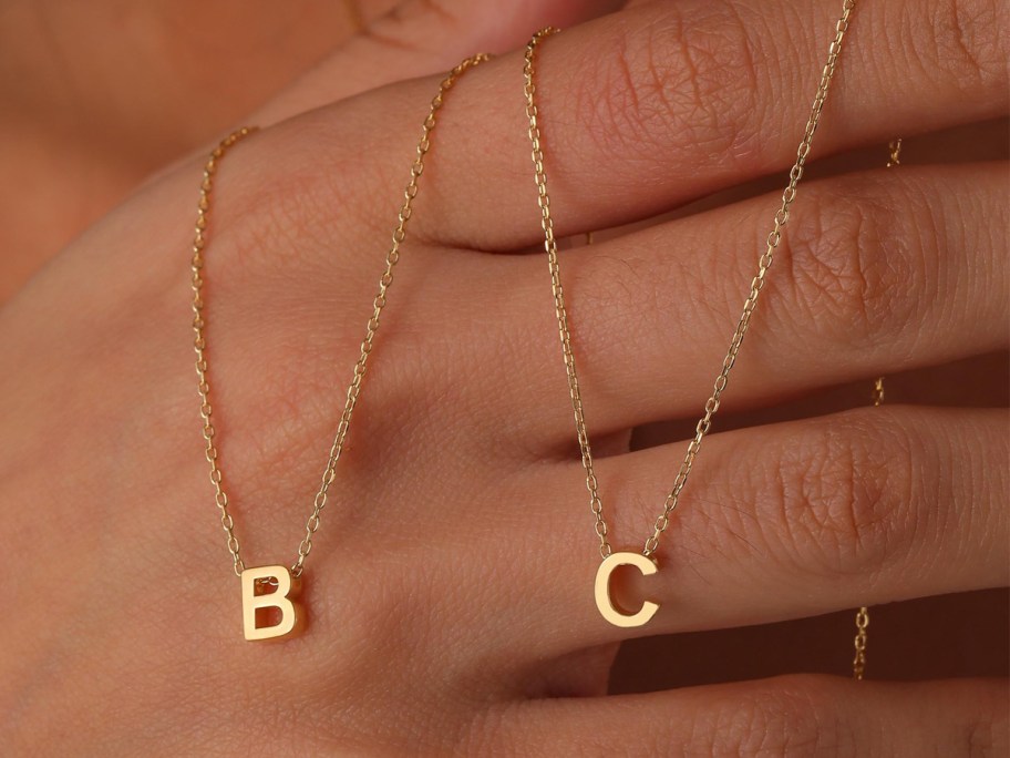 hand holding gold B & C initial necklaces