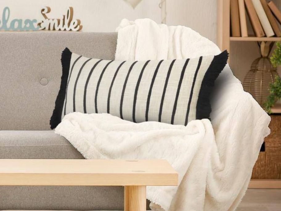 LR Home Fringed Ivory & Black Striped Cuddle Poly-Fill 28in x 12in Indoor Throw Pillow on couch