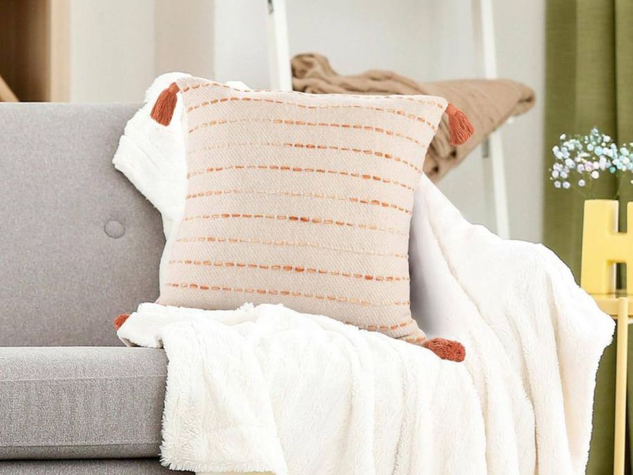 LR Home Torrent Orange Striped Hand-Woven Tasseled 20in x 20in Indoor Throw Pillow on couch
