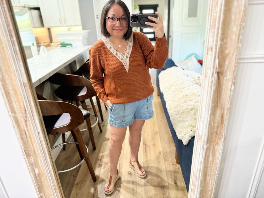 woman taking selfie in mirror wearing burnt orange sweater