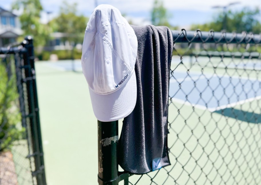 hat and towel hanging on fence