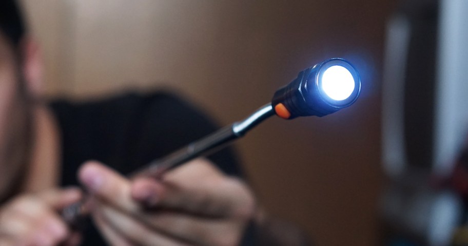 man holding a telescoping magnetic pickup tool flashlight