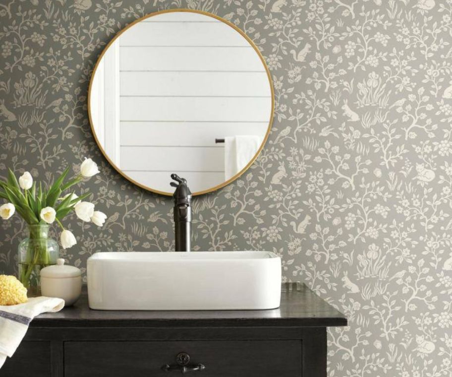 a bathroom sink in a wallpapered room