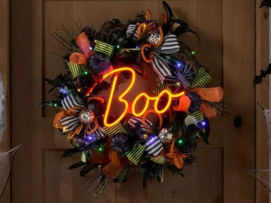 A Halloween wreath with a neon sign "Boo" in the middle of it 