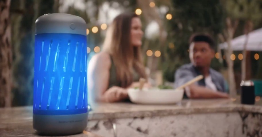 people sitting behind an illuminated Mosquito Zapper