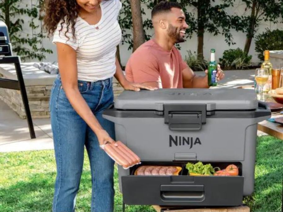 Woman getting a pack of hot dogs out of the drawer on a Ninja Frostvault Cooler