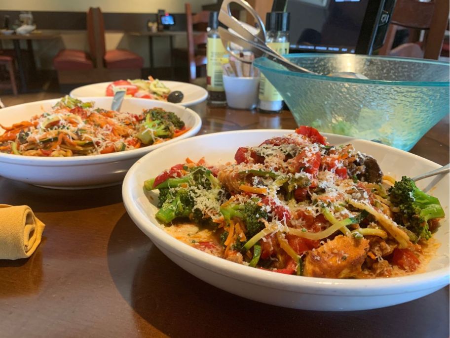 Table with two Olive Garden Entrees and a bowl of salad