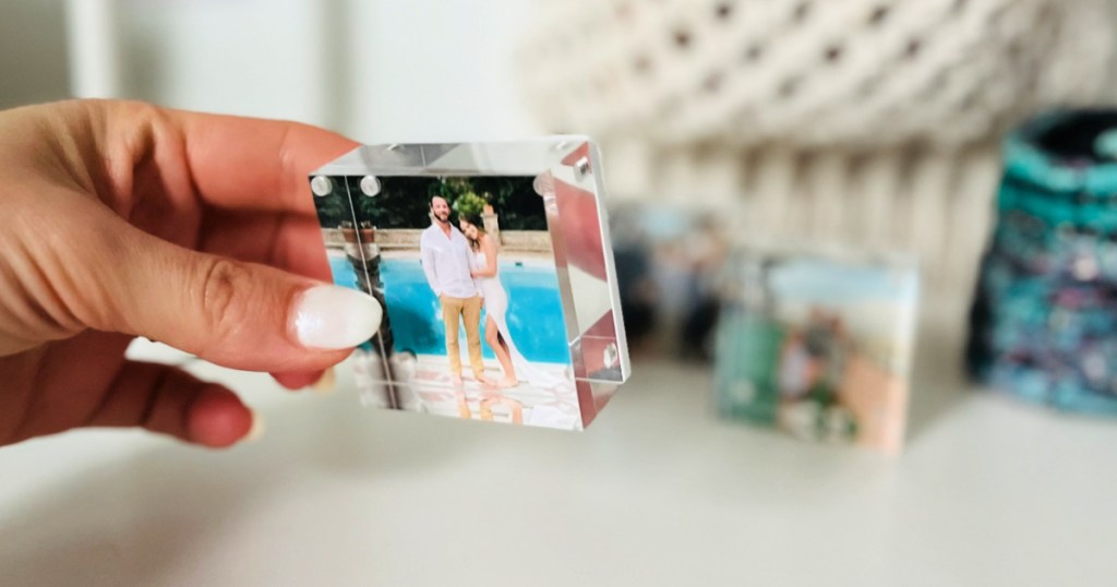 Woman holding up clear photo block featuring man & woman 