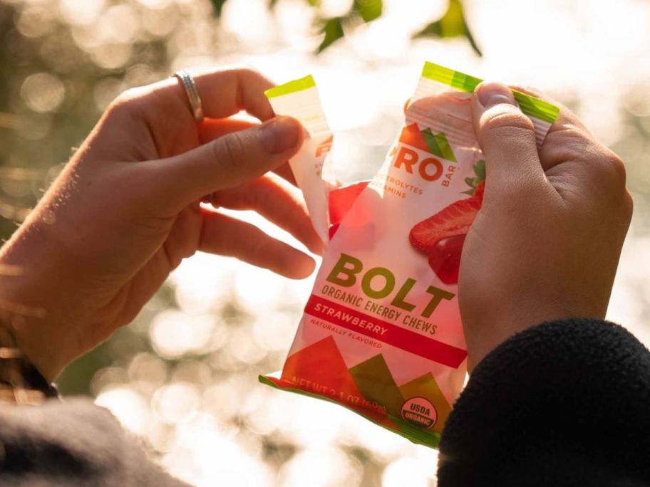 A person holding a packet of Pro Bar Bolt Energy Chews in Strawberry