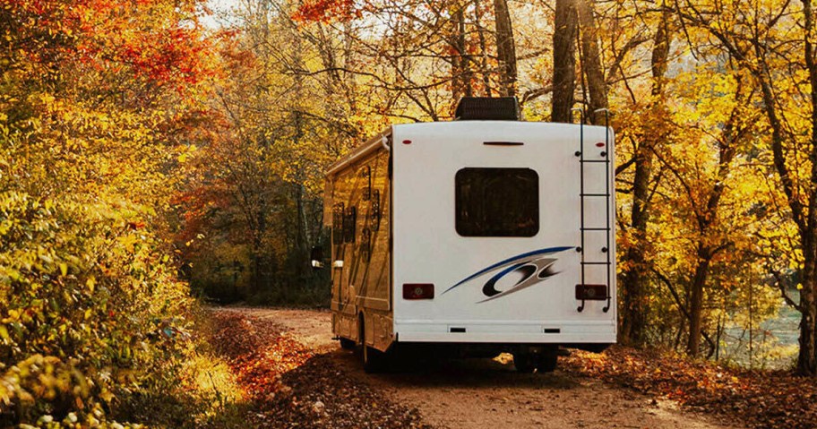 rv driving through trees with colorful fall leaves