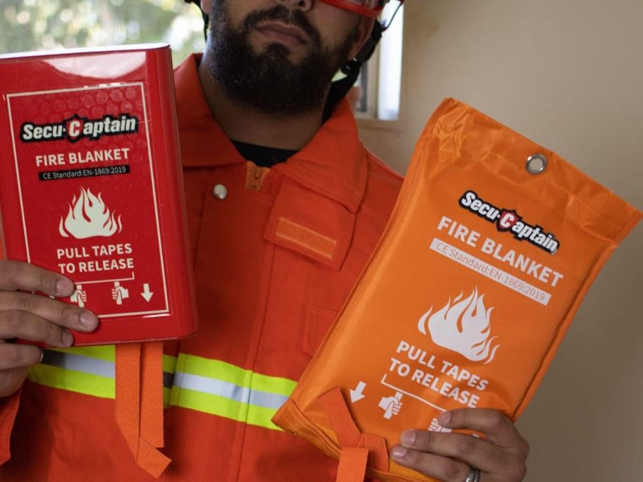 A firefighter holding 2 SecuCaptain Emergency Fire Blankets