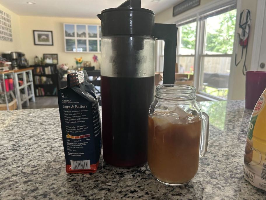 cold brew coffee maker sitting on countertop with bag of beans and mason jar mug