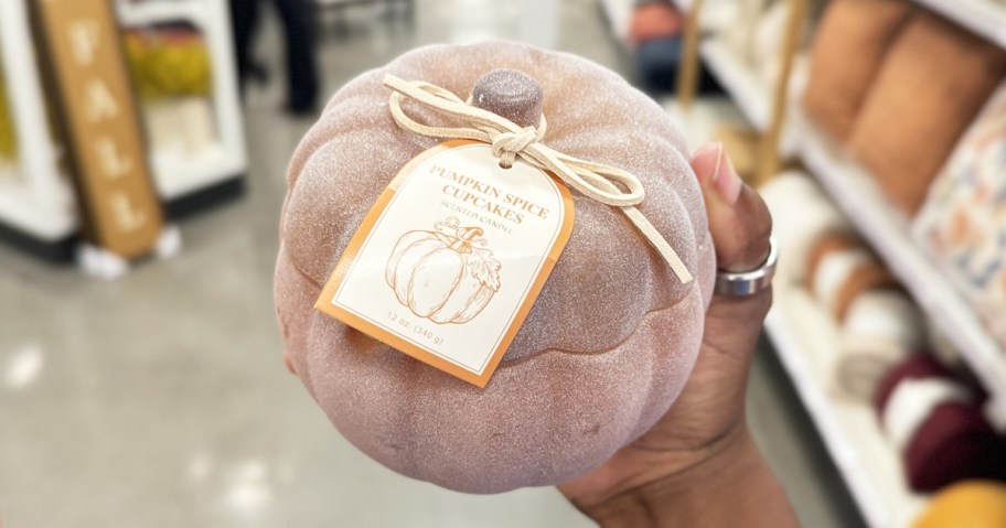 hand holding up a frosted glass pumpkin candle