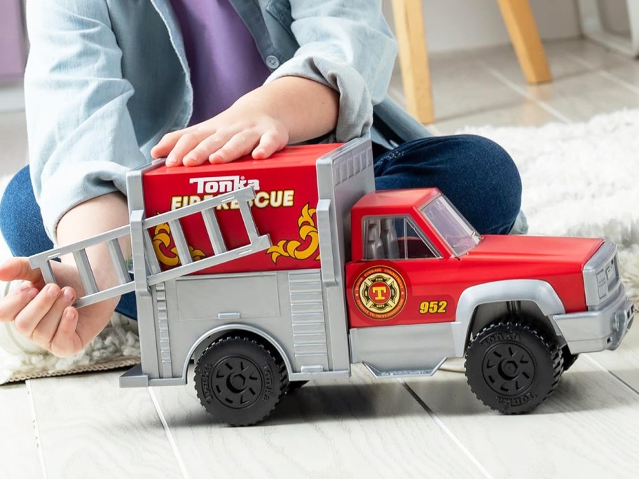 girl playing with a red tonka rescue truck