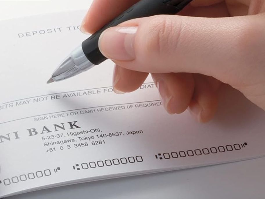 Hand using a Uniball pen to write a check