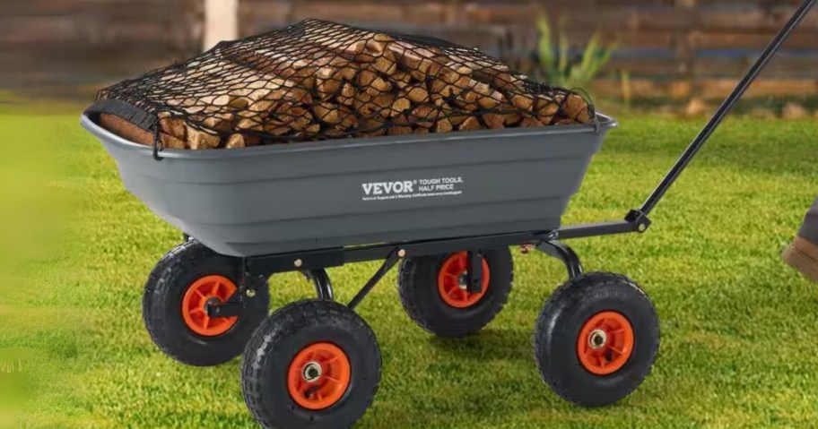 grey garden dump cart with black and orange wheels filled with chopped wood