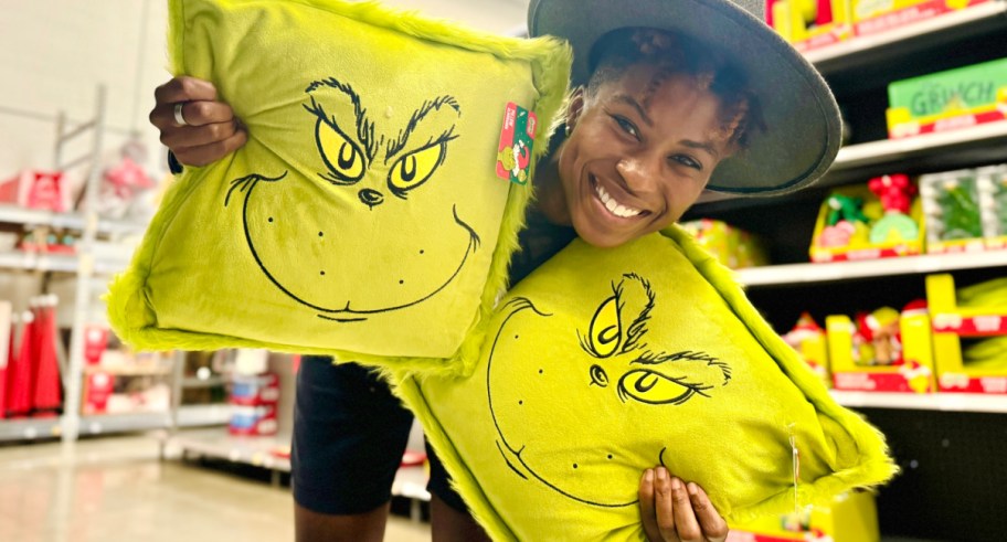 Woman holding grinch throw pillow at walmart